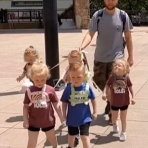 They are humans, not DOGS’: Father-of-five sparks furious debate after using a ‘LEASH’ to take his five-year-old quintuplets for a walk – but he insists it allows them to ‘do fun stuff without being stressed’. Full Story in the comments …